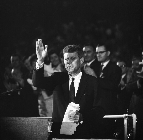 FILE - In this July 15, 1960, file photo, Sen. John F. Kennedy waves to the 65,000 persons who gathered in the Los Angeles Coliseum to hear him accept the Democratic nomination for U.S. President. The Olympic torch at Los Angeles Memorial Coliseum was lit Wednesday, July 15, 2020, to mark the 60th anniversary of John F. Kennedy's acceptance of the Democratic Party nomination for president at the historic stadium. Kennedy delivered what became known as "The New Frontier" speech on July 15, 1960, during the Democratic National Convention. The Coliseum hosted the 1932 and 1984 Olympics and Los Angeles is scheduled to hold a third Olympics in 2028. (AP Photo/File)