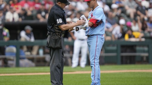 Umpire Lance Barrett, left, wipes the arm of St. Louis Cardinals relief pitcher Giovanny Gallegos with a towel during the eighth inning of a baseball game against the Chicago White Sox, Saturday, July 8, 2023, in Chicago. (AP Photo/Erin Hooley)