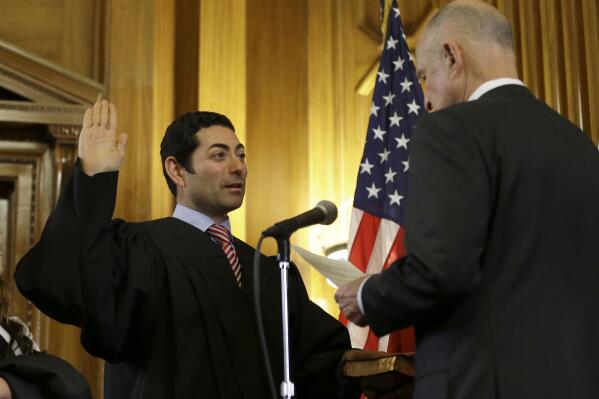 FILE - In this Jan. 5, 2015 file photo Mariano-Florentino Cuellar, left, is sworn in as an associate justice to the California Supreme Court by Gov. Jerry Brown during an inauguration ceremony in Sacramento, Calif. Cuellar announced, Thursday Sept. 16, 2021, that he will be leaving the state's high court in October 2021. (AP Photo/Rich Pedroncelli, file)