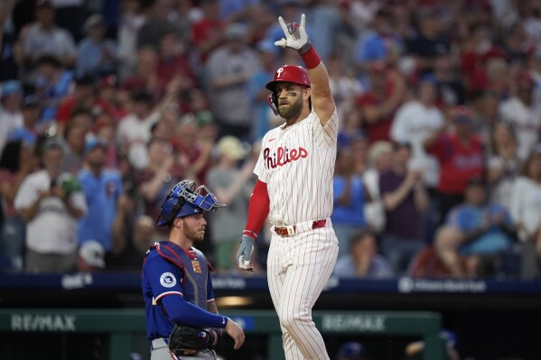 Philadelphia Phillies' Bryce Harper, right, reacts past Texas Rangers catcher Jonah Heim after hitting a home run against pitcher Jacob Latz during the sixth inning of a baseball game, Tuesday, May 21, 2024, in Philadelphia. (AP Photo/Matt Slocum)