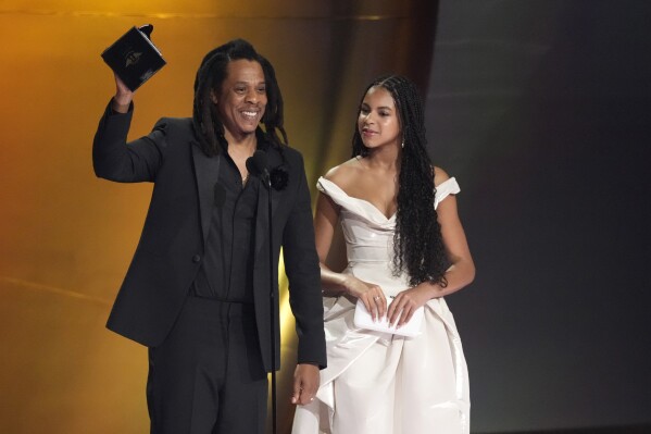 2024 年 2 月 4 日星期日，在洛杉矶举行的第 66 届格莱美颁奖典礼上，Jay-Z（左）作为女儿 Blue Ivy Carter 接受 Dr. Dre 全球影响力奖。  （美联社照片/克里斯·皮泽罗）
