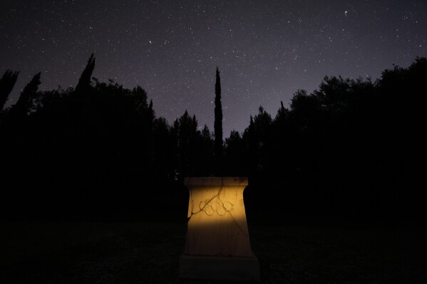 A marble altar with the Olympic rings stands under the night sky at the monument where is placed the heart of French Baron Pierre de Coubertin, in ancient Olympia, on Monday April 8, 2024. Born in 1863, Coubertin was the second president of the IOC - after Greece's Demetrios Vikelas - serving from 1896-1927. His tenure included the games held in Paris in 1900 and 1924. (AP Photo/Petros Giannakouris)