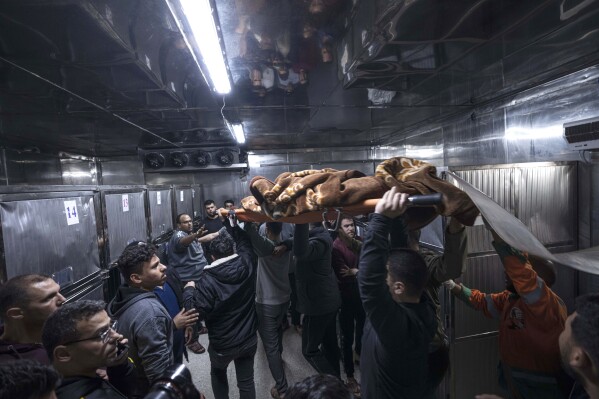 FILE - The body of a Palestinian killed in an Israeli airstrike, is carried into the morgue of Shifa Hospital in Gaza City, Tuesday, May 9, 2023. As Israeli warplanes pummel Gaza to avenge the Hamas attack, Palestinians say the military has largely unleashed its fury on civilians. (AP Photo/Fatima Shbair, File)