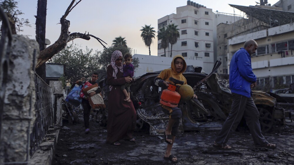 Palestinians carry belongings as they leave al-Ahli hospital, which they were using as a shelter, in Gaza City, Wednesday, Oct. 18, 2023. The Hamas-run Health Ministry says an Israeli airstrike caused the explosion that killed hundreds at al-Ahli hospital, but the Israeli military says it was a misfired Palestinian rocket. (AP Photo/Abed Khaled)