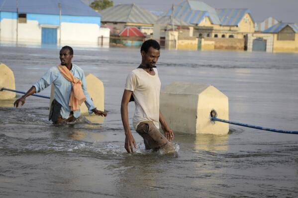 Men walk through floodwaters on a street in the town of Beledweyne, in Somalia Monday, May 15, 2023. Estimates from the UN Office for the Coordination of Humanitarian Affairs are that 460,000 people have been affected by flooding caused by heavy rains since mid-March. (AP Photo)