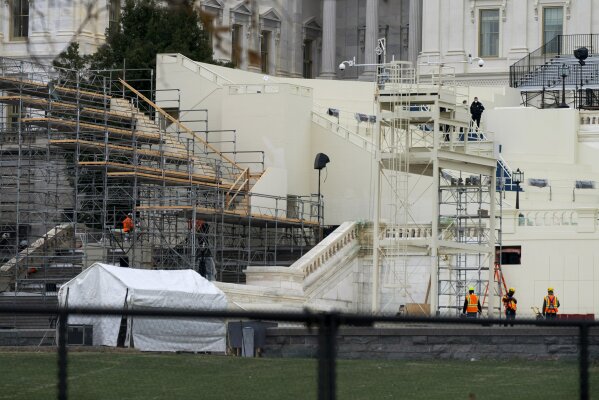 Seen over new security fencing at bottom, workers fix inaugural stands and platforms that were damaged Friday, Jan. 8, 2021, at the U.S. Capitol in Washington, after Wednesday's riot. (AP Photo/Jacquelyn Martin)