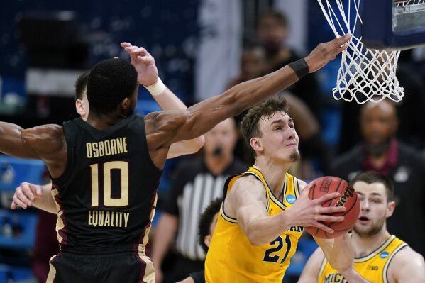 Michigan guard Franz Wagner (21) drives to the basket ahead of Florida State forward Malik Osborne (10) during the first half of a Sweet 16 game in the NCAA men's college basketball tournament at Bankers Life Fieldhouse, Sunday, March 28, 2021, in Indianapolis. (AP Photo/Jeff Roberson)