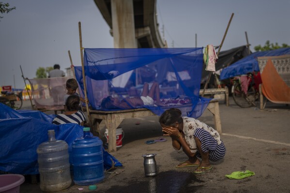 Rekha Devi, a 30-year-old farm worker, washes her face next to her temporary shelter on an under construction overpass after her family evacuated the flooded banks of the Yamuna River in New Delhi, India, Wednesday, Aug. 9, 2023. Devi, her husband and their children fled as July's record monsoon rains triggered flooding that killed more than 100 people in northern India, displaced thousands and inundated large parts of the capital city. (AP Photo/Altaf Qadri)