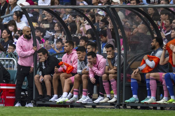 Inter Miami's Lionel Messi, sixth from left, looks on from the bench during the friendly football match between Hong Kong Team and US Inter Miami CF at the Hong Kong Stadium in Hong Kong, Sunday, Feb. 4, 2024. (AP Photo/Louise Delmotte)