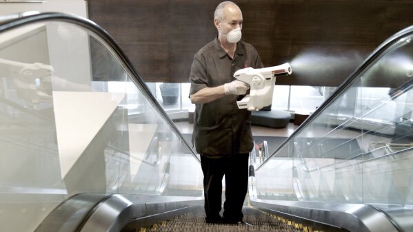 In this April 2020 photo provided by Marriott, a Marriott associate using an electrostatic sprayer to clean public areas at the Brooklyn Bridge Marriott in New York.  Marriott, Hilton and other big hotel companies are used to competing on price or perks. Now they are competing on cleanliness.  From masked clerks at the front desk to shuttered buffets, hotels are making visible changes in the wake of the coronavirus pandemic.  (Marriott via AP)