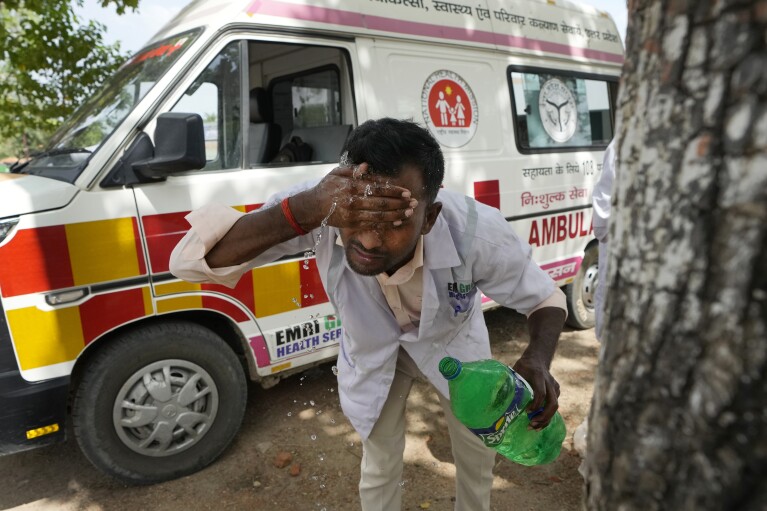 Jitendra Kumar, a paramedic who travels in ambulance, washes his face with water to cool himself off after dropping a patient at Lalitpur district hospital, in Banpur, in Indian state of Uttar Pradesh, Saturday, June 17, 2023. (AP Photo/Rajesh Kumar Singh)