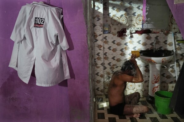 Sunil Kumar Naik, an ambulance driver, bathes as he gets ready for the day, in Banpur in the Indian state of Uttar Pradesh, Sunday, June 18, 2023. Ambulance drivers and other healthcare workers in rural India are the first line of care for those affected by extreme heat. (AP Photo/Rajesh Kumar Singh)