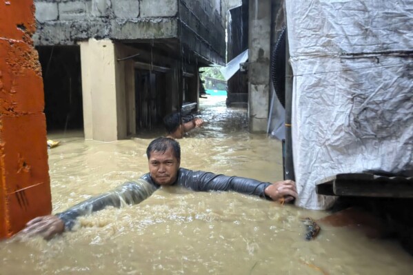 A man negotiates neck-deep floodwaters in his village caused by Typhoon Doksuri in Laoag city, Ilocos Norte province, northern Philippines, Wednesday, July 26, 2023. Typhoon Doksuri blew ashore in a cluster of islands and lashed northern Philippine provinces with ferocious wind and rain Wednesday, leaving at least a few people dead and displacing thousands of others as it blew roofs off rural houses, flooded low-lying villages and toppled trees, officials said. (AP Photo/Bernie Sipin Dela Cruz)