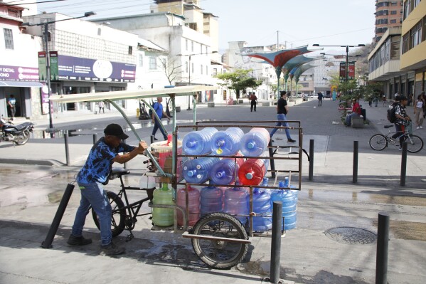 A man transports plastic water in downtown Maracay, Venezuela, Saturday, March 22, 2025. (AP Photo/Cristian Hernandez)