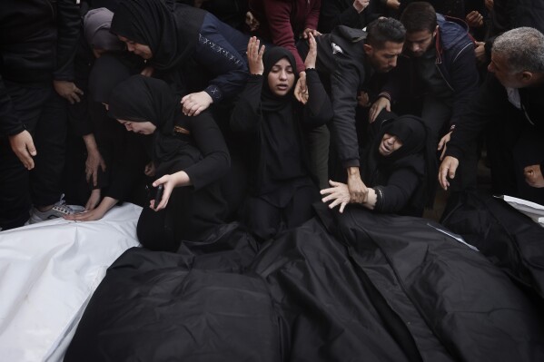 Palestinians mourn relatives killed in an Israeli bombardment in the Gaza Strip outside a morgue in Khan Younis, Wednesday, Dec. 20, 2023.  (AP Photo/Mohammed Tahman)