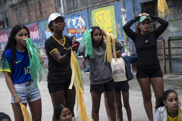Residents watch the Women's World Cup match between Brazil and Jamaica, on a television set up by the Mandela Stars Project, in the Manguinhos favela, in Rio de Janeiro, Brazil, Wednesday, Aug. 2, 2023. Jamaica advanced to the knockout round, in Melbourne, Australia, for the first time following a 0-0 draw that ended Brazil’s run in the group stage for the first time since 1995 at the Women’s World Cup. (AP Photo/Bruna Prado)