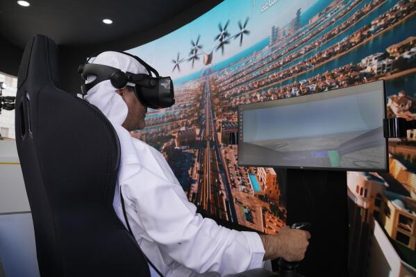 A man experiences a driving simulator of a flying taxi at the Dubai Roads and Transportation Authority's stand during the World Government SummitWLD in Dubai, United Arab Emirates, Monday, Feb 13, 2023. Dubai again is planning for the takeoff of flying taxis in this futuristic city-state on the Arabian Peninsula, offering its firmest details yet Monday for a pledged launch by 2026. (AP Photo/Kamran Jebreili)