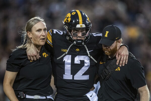 Iowa quarterback Cade McNamara (12) is helped off the field after an injury during an NCAA college football game against Michigan State, Saturday, Sept. 30, 2023, in Iowa City, Iowa. (Nick Rohlman/The Gazette via AP)