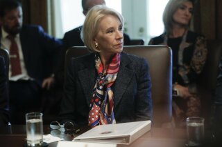 In this Oct. 21, 2019, photo, Education Secretary Betsy DeVos listens to President Donald Trump during a Cabinet meeting in the Cabinet Room of the White House in Washington. A federal judge has held DeVos in contempt of court for violating an order to stop collecting loans from thousands of former for-profit college students. (AP Photo/Pablo Martinez Monsivais)