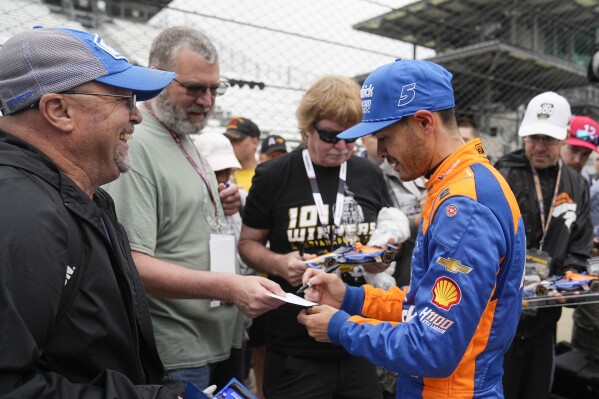 Kyle Larson signs autographs for fans during a practice session for the Indianapolis 500 auto race at Indianapolis Motor Speedway, Tuesday, May 14, 2024, in Indianapolis. (AP Photo/Darron Cummings)