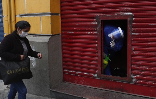 An employee calls for a client to enter a fast food restaurant, during a government lockdown restricting residents to essential shopping in the mornings in an attempt to contain the spread of the new coronavirus, in La Paz, Bolivia, Tuesday, May 5, 2020. (AP Photo/Juan Karita)