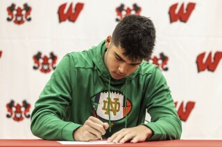 FILE - Omaha Westside linebacker Teddy Rezac signs a letter of intent to play NCAA college football at Notre Dame, Wednesday, Dec. 20, 2023, in Omaha. College football's early signing period will move up from mid-December to the week preceding conference championship games, starting in 2024. (Chris Machian/Omaha World-Herald via AP, File)