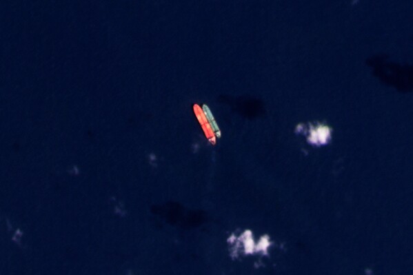 FILE - In this satellite photo provided by Planet Labs PBC, vessels identified as the Virgo, left, and the Suez Rajan, by the advocacy group United Against Nuclear Iran, are seen in the South China Sea on Feb. 13, 2022. An American-owned oil tanker long suspected of carrying sanctioned Iranian crude oil began offloading its cargo near Texas late Saturday, Aug. 19, 2023, tracking data showed, even as Tehran has threatened to target shipping in the Persian Gulf over it. (Planet Labs PBC via AP, File)