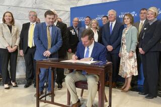 Kentucky Gov. Andy Beshear signs a health care bill into law on Monday, March 20, 2023, in Frankfort, Ky. Beshear signed into law the bipartisan measure that's meant to bolster access to health care across the state by injecting additional funding into hospitals. (AP Photo/Bruce Schreiner)