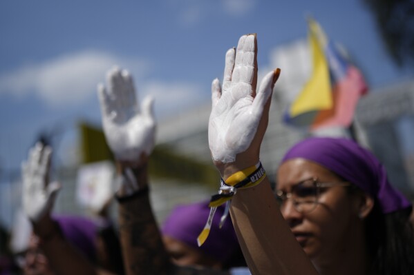People with their hands painted white march on International Women's Day in Caracas, Venezuela, Friday, March 8, 2024. (AP Photo/Ariana Cubillos)