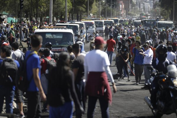 Service trucks line up to remove trash left behind by anti-austerity protesters, in Quito, Ecuador, Monday, Oct. 14, 2019. Thousands of indigenous demonstrators, student volunteers and local residents launched a massive cleanup Monday morning of a Quito park where anti-austerity protesters fought police for days, leaving piles of burning tires, trees and construction material. (AP Photo/Fernando Vergara)