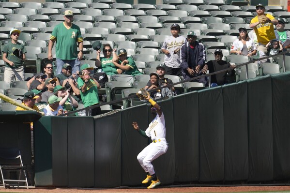 Fans watch as Oakland Athletics left fielder Esteury Ruiz catches a fly out in foul territory hit by Detroit Tigers' Akil Baddoo during the fifth inning of a baseball game in Oakland, Calif., Saturday, Sept. 23, 2023. (AP Photo/Jeff Chiu)