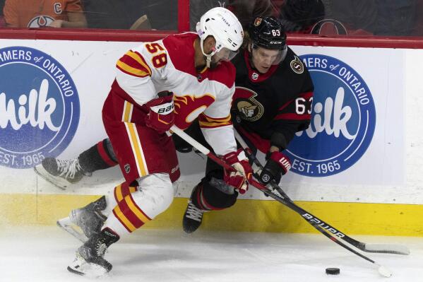 Calgary Flames defenseman Oliver Kylington (58) knocks Ottawa Senators right wing Tyler Ennis off the puck during the first period of an NHL hockey game, in Ottawa, Ontario, Sunday, Nov. 14, 2021. (Adrian Wyld/The Canadian Press via AP)