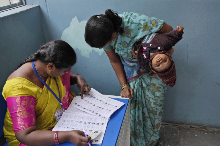 FILE-A woman checks for her name before casting her vote at a polling station during the Telangana state assembly elections in Hyderabad, India, Thursday, Nov. 30, 2023. From April 19 to June 1, nearly 970 million Indians - or over 10% of the world’s population - will vote in the country's general elections. The mammoth electoral exercise is the biggest anywhere in the world - and will take 44 days to complete before results are announced on June 4. (AP Photo/Mahesh Kumar A,File)