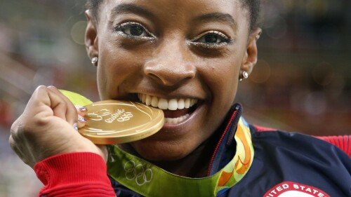 La gimnasta estadounidense Simone Biles muerde su medalla de oro tras ganar la medalla de oro en el concurso completo de los Juegos Olímpicos de Río de Janeiro 2016, el 11 de agosto de 2016. (AP Foto/Dmitri Lovetsky)