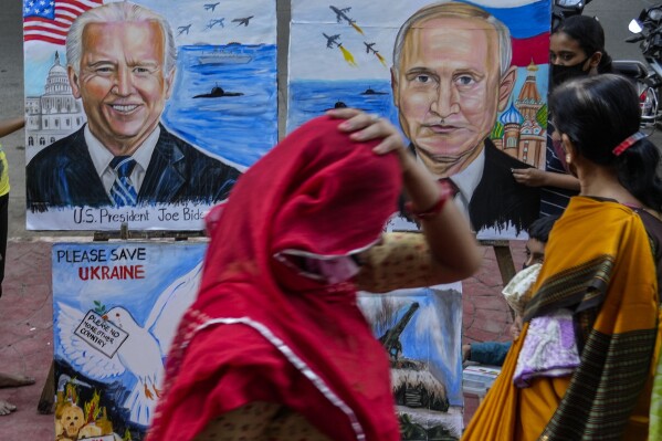 FILE- A woman adjusts her sari as she walks past art works by students calling for peace amid fears of a Russian offensive on Ukraine, on a pavement in Mumbai, India, Feb. 21, 2022. Ahead of the G20 summit of leading economies, India has promoted itself as a rising global star with the potential to bridge the gap between the West and Russia. That stance also will be put to the test during the summit. So far, none of the G20 meetings this year have been able to agree on wording about Russia's war in Ukraine. (AP Photo/Rafiq Maqbool, File)