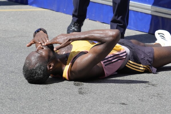 Sisay Lemma, of Ethiopia, blows kisses as he celebrates while lying down near the finish line after winning the Boston Marathon, Monday, April 15, 2024, in Boston. (AP Photo/Steven Senne)