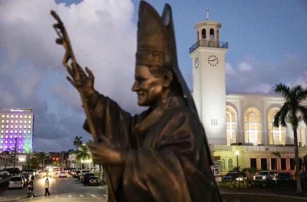 FILE - In this Tuesday, May 7, 2019 file photo, a statue of Pope John Paul II stands outside the island's main cathedral, Dulce Nombre de Maria Cathedral-Basilica, during a Mass in Hagatna, Guam. Over 200 clergy abuse lawsuits led church leaders in the U.S. territory to seek bankruptcy protection, as they estimated at least $45 million in liabilities. Even so, the Archdiocese of Agana’s parishes, schools and other organizations have received at least $1.7 million in coronavirus rescue funds, even as it sues the Small Business Administration for approval to get a loan for its headquarters, according bankruptcy filings. (AP Photo/David Goldman)