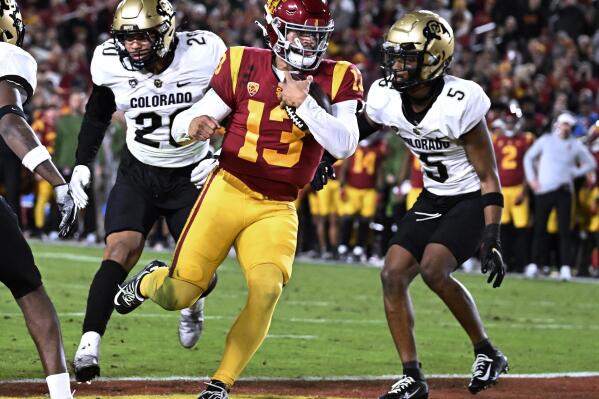 Southern California quarterback Caleb Williams scores a touchdown, getting past Colorado's Robert Barnes, left, and Tyrin Taylor during the first half of an NCAA college football game Friday, Nov. 11, 2022, in Los Angeles. (AP Photo/John McCoy)