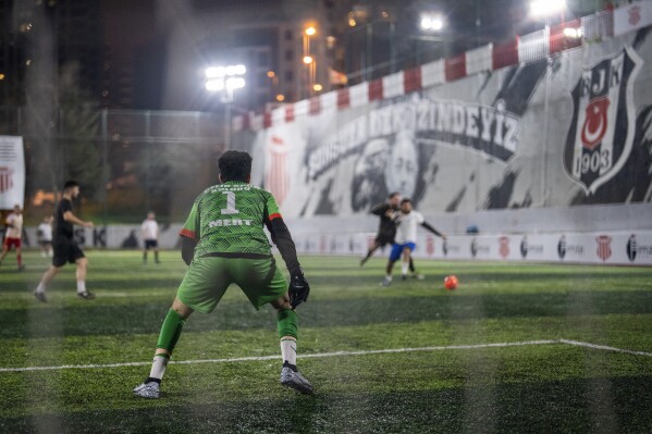 Amateur goalkeeper Mustafa Mert Olcer, left, follows the action during a recreational soccer "Astroturf" match in Istanbul, Turkey, Tuesday, March 5, 2024. More than a few times a week, the 18-year-old courier and passionate goalkeeper Mustafa Mert Olcer, gets a call from Rent-a-Goalkeeper to man a goalpost. (AP Photo/Francisco Seco)