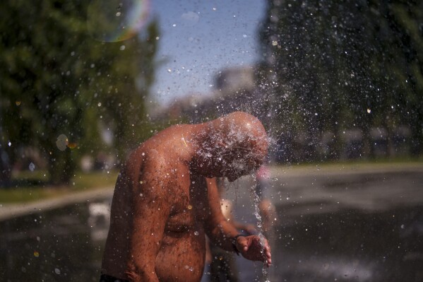 A man cools off at an urban beach at Madrid Rio park in Madrid, Spain, Monday, June 26, 2023. The entire planet sweltered for the two unofficial hottest days in human recordkeeping Monday and Tuesday, according to University of Maine scientists at the Climate Reanalyzer project. The unofficial heat records come after months of unusually hot conditions due to climate change and a strong El Nino event. (AP Photo/Manu Fernandez)