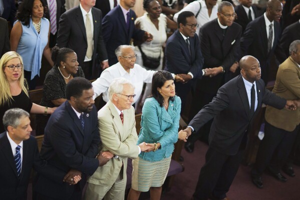 FILE - Then-South Carolina Gov. Nikki Haley, center right, joins hands with Charleston Mayor Joseph Riley, left, and Sen. Tim Scott, R-S.C., right, at a memorial service at Morris Brown AME Church in Charleston, S.C., June 18, 2015. Haley and Scott attended the funerals of those slain by a racist gunman at Mother Emanuel AME Church. Scott would later tear up on the Senate floor recounting the faith of the fallen and their families. Haley would go on to write that she leaned on God and her faith deepened as she grappled with the trauma of the Charleston shooting. (AP Photo/David Goldman, File)