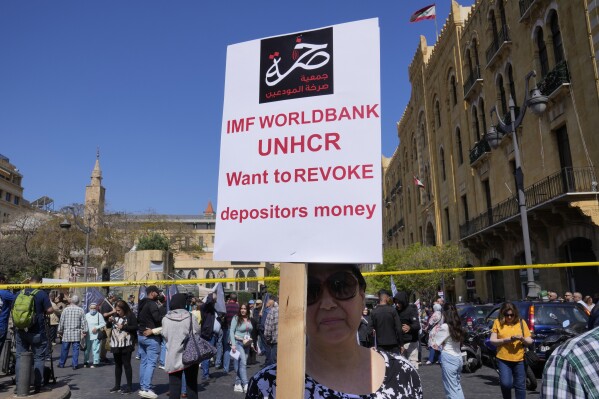 FILE - A protesting depositor carries a placard at a protest near Parliament in downtown Beirut, Lebanon, Tuesday, May 9, 2023. Poverty in Lebanon tripled over the course of a decade during which the small Mediterranean country slid into a protracted financial crisis, the World Bank said Thursday, May 23, 2024. (AP Photo/Hussein Malla, File)
