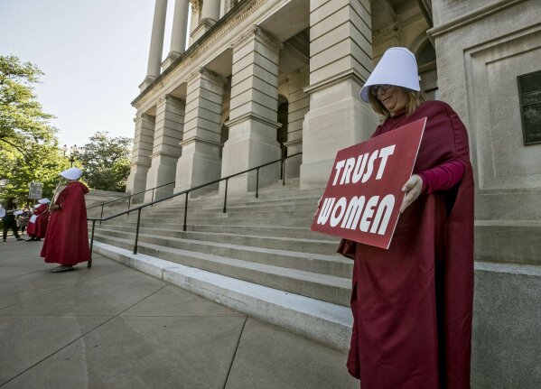 File-Michelle Disher, from Roswell, and others dressed as characters from "The Handmaid's Tale", protest outside the Capitol where Georgia's Republican Gov. Brian Kemp, was to sign the legislation, Tuesday, May 7, 2019, in Atlanta, banning abortions once a fetal heartbeat can be detected, which can be as early as six weeks before many women know they're pregnant.  A federal judge is permanently blocking Georgia’s 2019 “heartbeat" abortion law, finding that it violates the U.S. Constitution. U.S. District Judge Steve Jones ruled against the state Monday, July 13, 2020, in a lawsuit filed by abortion providers and an advocacy group. (Bob Andres/Atlanta Journal-Constitution via AP, File)