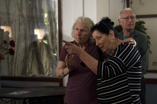 Osnat Peri, right, whose husband, Haim, is in Hamas captivity, takes part in a Passover Seder commemoration with relatives of hostages held in the Gaza Strip, at the communal dining room at Kibbutz Nir Oz, Thursday, April 11, 2024. For many Jews, no matter how observant, Passover is a time to unite with family to eat and drink around what's known as a Seder table, remembering how the Jews persevered through harsh times. But this year, when Passover begins on Monday, many families are torn on how to celebrate, or if it's worth acknowledging at all. (AP Photo/Maya Alleruzzo)