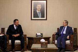 FILE - Syrian Foreign Minister Faisal Mekdad, right, meets with Russian lawmaker Dmitry Sablin, who visits Syria as part of a large Russian delegation that includes the foreign minister for the breakaway pro-Russian area in Ukraine, the so-called "Donetsk People's Republic", in Damascus, Syria, Tuesday, June 14, 2022. Syria said Wednesday, July 20, 2022, that it is formally breaking diplomatic ties with Ukraine in response to a similar move by Kyiv. Syria is a strong ally of Russia, which joined Syria’s conflict in September 2015 in favor of President Bashar Assad. (AP Photo/Omar Sanadiki, File)