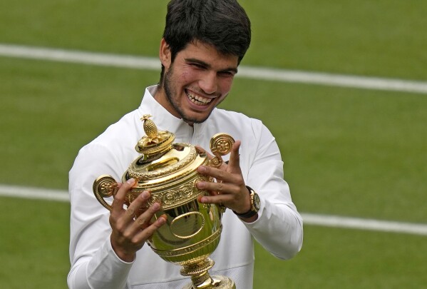 Spain's Carlos Alcaraz celebrates with the trophy after beating Serbia's Novak Djokovic to win the final of the men's singles on day fourteen of the Wimbledon tennis championships in London, Sunday, July 16, 2023. (AP Photo/Alastair Grant)