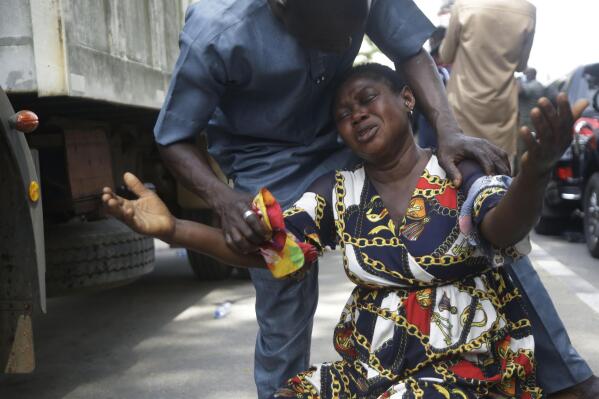 A relative of a missing person cries at the site of a collapsed 21-story apartment building under construction in Lagos, Nigeria, Wednesday, Nov. 3, 2021. The number of bodies recovered at the site of the building that collapsed in Nigeria has risen to 21, the Lagos governor said Wednesday, admitting that the search and rescue mission is "still a very difficult, a very long procedure." On day three of the search operation at the Ikoyi area of Lagos, excavators combed through the pile of debris while oxygen and water were intermittently pumped into the rubble as the search continues. (AP Photo/Sunday Alamba)