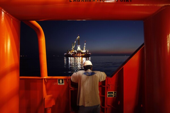 FILE - Wilson Ruiz, a crew member of the Joe Griffin, looks out at the oil slick at the site of the BP Deepwater Horizon offshore oil rig collapse in the Gulf of Mexico on May 6, 2010. The Biden administration has tightened offshore oil drilling safety regulations, including rules regarding the use of “blowout preventer” devices on offshore oil and gas drilling rigs. Planned changes announced last fall were finalized Tuesday, Aug. 22, 2023 — more than 13 years after the BP Deepwater Horizon disaster that killed 11 workers and spewed an estimated 130 million gallons of oil into the Gulf of Mexico. (AP Photo/Gerald Herbert, File)