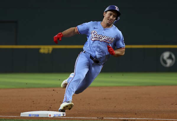Texas Rangers' Wyatt Langford rounds third base on an inside-the-park home run against the Cincinnati Reds in the first inning of a baseball game, Sunday, April 28, 2024, in Arlington, Texas. (AP Photo/Richard W. Rodriguez)
