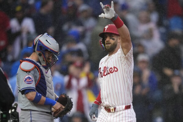 Philadelphia Phillies' Bryce Harper, right, reacts past New York Mets catcher Tomas Nido after hitting a home run during the first inning of a baseball game, Wednesday, May 15, 2024, in Philadelphia. (AP Photo/Matt Slocum)